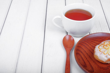 A cup of tea and sweet donut on wooden plate over  wooden tabletop with wooden  spoon. Celebration concept