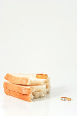 Two separate wedding rings with torn bread meaning to the word divorce.