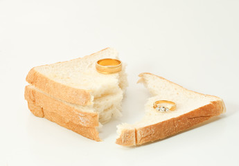 Two separate wedding rings with torn bread meaning to the word divorce.