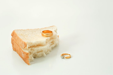 Two separate wedding rings with torn bread meaning to the word divorce.