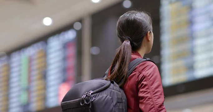 Travel woman look at the flight number display board at airport