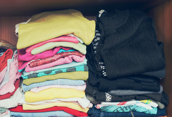 Pile of T-shirt clothes in closet. Stack of many color folded woman shirts overlay.