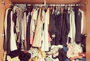 Pile of messy clothes in closet. Untidy cluttered woman wardrobe in vintage style.