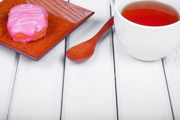 A cup of tea and sweet donut on wooden plate over  wooden tabletop with wooden  spoon. Celebration concept