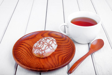 A cup of tea and sweet donut on wooden plate over  wooden tabletop with wooden  spoon. Celebration concept