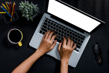 Woman hands typing on keyboard in office desk, laptop with blank screen for product display.Top view, Flat lay