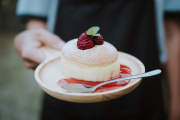 Woman Chef hand holding Japanese cheesecake with jam, Close up.