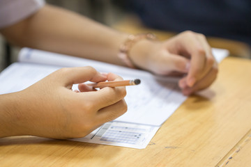 Student taking exams, writing examination on paper answer sheet optical form of standardized test...