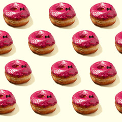 Doughnuts with pink frosting on pale yellow background