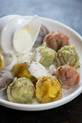 Boiled colored dumplings pelmeni with sour cream, close-up, selective focus