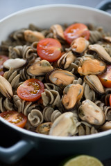 Close-up of pasta made of hemp flour and served with tomatoes and mussels, vertical shot
