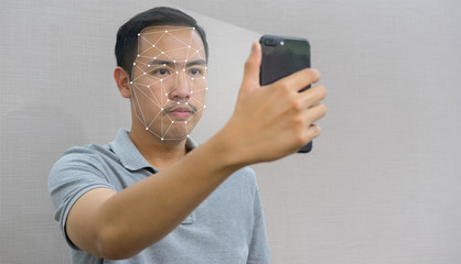 close up on asian man holding smartphone and using face scan recognition technology for unlock and...
