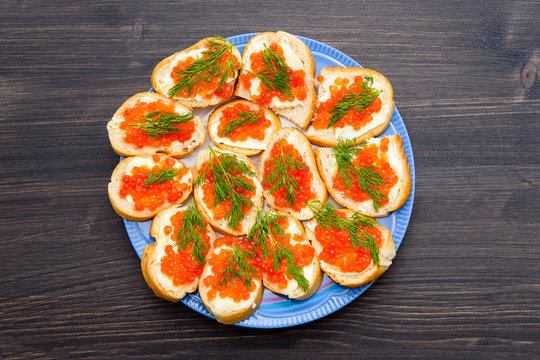 Sandwiches with butter and red caviar, green salad leaf, on a wooden rustic table. sandwich with red caviar. salmon roe. Sea food. Tasty delicious snack