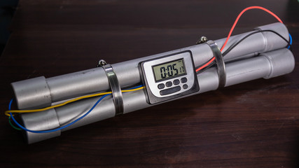 Pipe bomb with an clock timer to trigger detonation, on wooden table