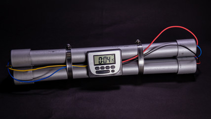 Pipe bomb with an clock timer to trigger detonation on black background