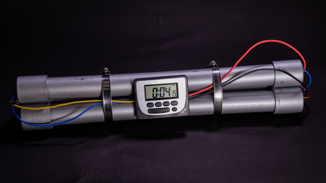Pipe bomb with an clock timer to trigger detonation on black background