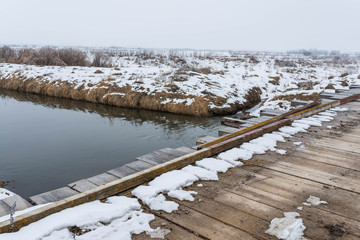 Fototapeta premium Old wood bridge over Olt river at wintertime in Romania.