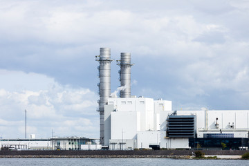 Obraz premium Waterside refinery letting off steam into atmosphere sitting right on a dyke on the famous dutch man made island.