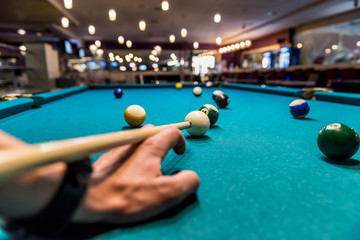 Hand as rack for cue on billiard table with balls