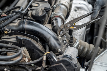 Fototapeta na wymiar Car engine, male hand and tool fixing nut