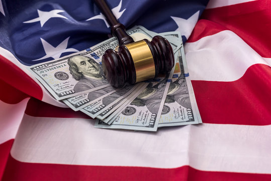 Judge's gavel with dollar banknotes on american flag