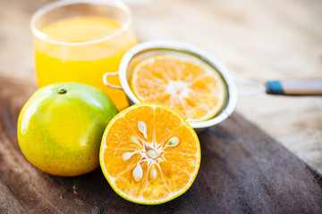 Fresh green tangerine orange fruit and juice on wooden table