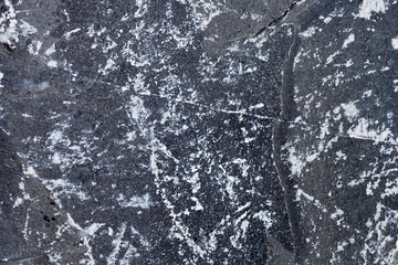 Detailed seaside etched stone surface with white grit and mold building from ocean waves crashing against it for many years.