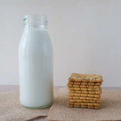 milk in bottle and cookie on wood