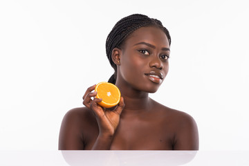 Natural spa. Beautiful young Afro-American shirtless woman holding pieces of orange while standing isolated on white background