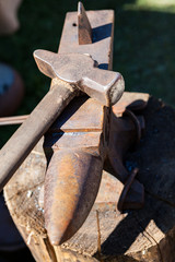 Old rusty iron anvil and hammer outdoors
