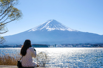 Woman sitting on the ground at kawaguchiko lake, Japan. View of fuji mountains.