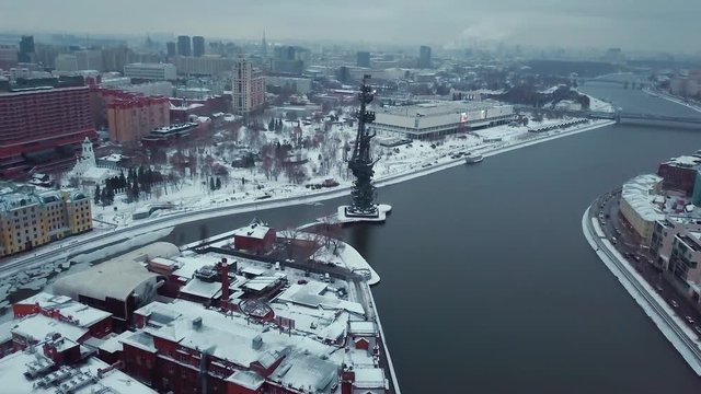 Drone flies over the Moscow River to the monument of Peter the Great. All roofs of buildings in the snow. Winter. Overcast weather.