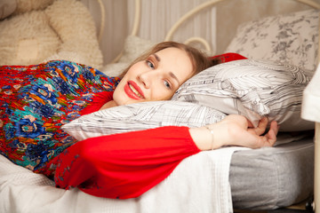 girl in red long evening dress in white bedroom by the bed with curtains © goldeneden