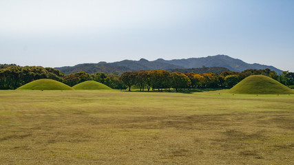 Tumuli royal tomb in autumn foliage backgroung. Gyeongju, South Korea.The Gyeongju Historic Areas...