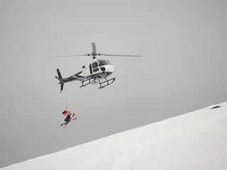 Gardinen Skifahrer-Freerider springt vom Hubschrauber-Heliski auf einen schneebedeckten Berg © Baikal360