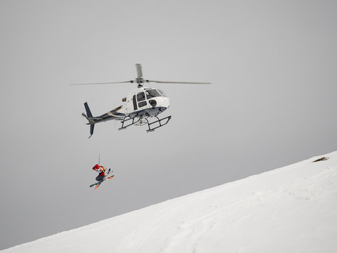 Skier freerider jumps from helicopter heliski on a snowy mountain
