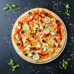 Italian pizza on a dark background, top view