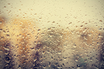 Raindrops on glass, window background view of buildings out of focus.