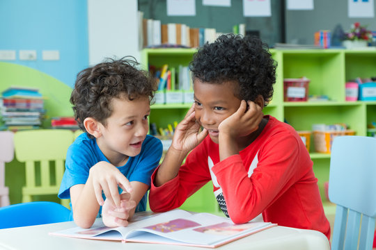 Two boy kid sit on table and reading tale book  in preschool library,Kindergarten school education concept.