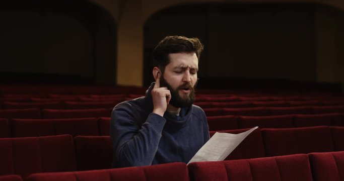 Medium shot of an actor rehearsing singing in the theater