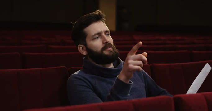 Medium shot of a man directing a scene in the theater