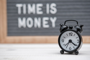 black alarm clock on the background of the inscription time is money