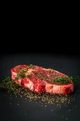 Poster Raw dry aged entrecote steak. Delicious barbecure rib eye steak with different spices on a dark stone plate. © JeDo