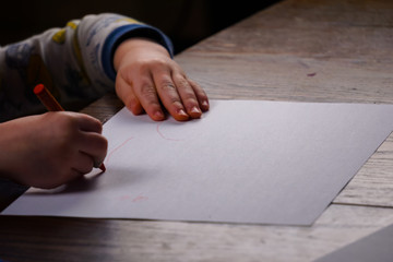 Fototapeta na wymiar Toddler sitting at table coloring on white paper.