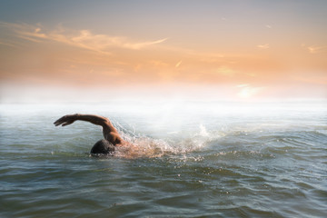 Fototapeta premium Man swimming in beautiful foggy sunrise