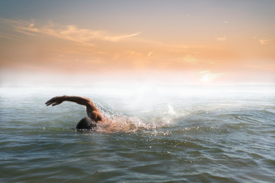 Man swimming in beautiful foggy sunrise - Powered by Adobe