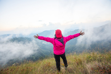 rear of happy woman stand on top mountain looking view with mist and cloud at Doi Langka Luang, Chiang Rai province. soft focus.