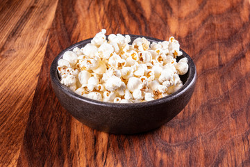 Salt popcorn on the wooden table. Popcorn in a stone bowl. Watching a movie with popcorn. Copy space. Pop corn.