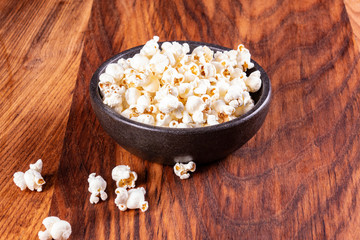 Salt popcorn on the wooden table. Popcorn in a stone bowl. Watching a movie with popcorn. Copy space. Pop corn.