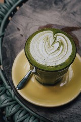 Matcha tea latte art with vegan coconut milk from above. Outdoor coffee shop table